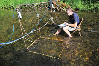 Michigan State University graduate student conducting research with PIT tags and antenae in Ocqueoc River